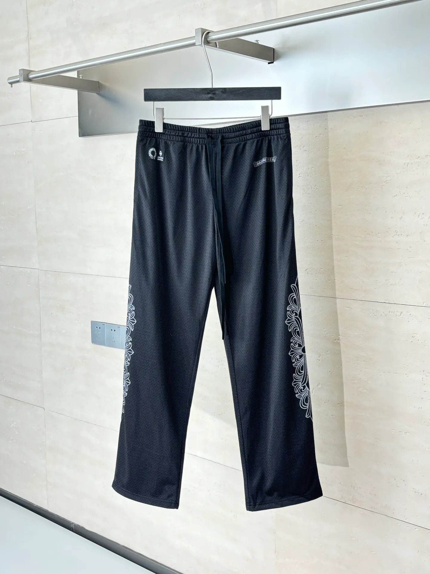 P340 Chrome Heart*/Chrome Heart Sanskrit mesh ice hockey suit straight trousers. The original version was purchased for 15,989 and developed. The fabric is made of custom weaving and dyeing technology. It is made of selected black mesh fabric, showing a unique sports style. The fabric has been specially treated to provide excellent breathability and comfort while maintaining a crisp and structured look. The double-layer design structure enhances the overall texture and makes the wearing experience more three-dimensional and full. The brand's iconic patterns are printed in many places, and high-precision printing technology is used to ensure that the patterns are clear and sharp. The silver printing has a glitter effect, showing charming luster changes under different lights. All printings undergo strict color difference control to ensure accurate color reproduction. The silver-plated pattern design on the sleeve arms is particularly eye-catching, showing the brand's consistent dark luxury style. In terms of details, the latest custom-woven labels are used, and the workmanship is exquisite. The overall shape is designed for both men and women, with both fashion and practicality. This T-shirt perfectly combines sports elements with high fashion craftsmanship, making it the brand's iconic street style item.  Size：S/M/L
